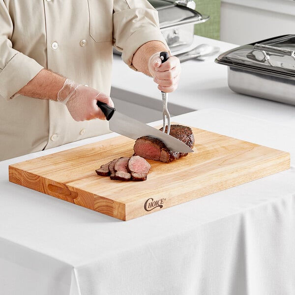 A person using a knife to cut meat on a Choice wooden cutting board.