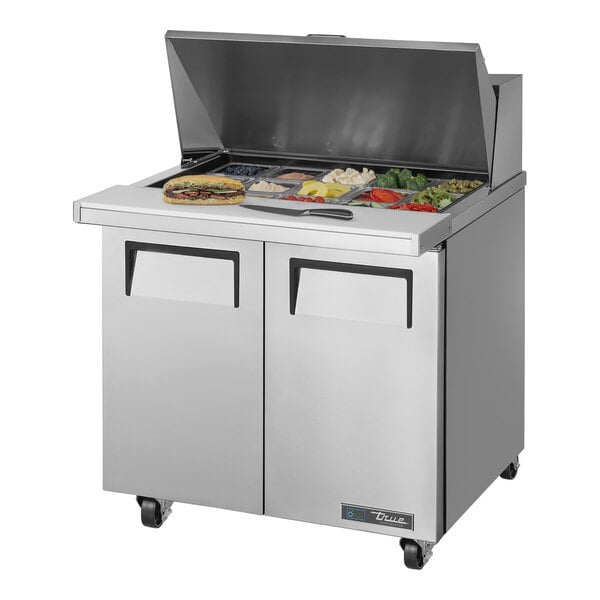 A True refrigerated sandwich prep table with food trays on the counter.