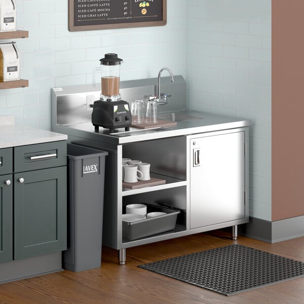 A Regency stainless steel beverage table with a sink on a kitchen counter.