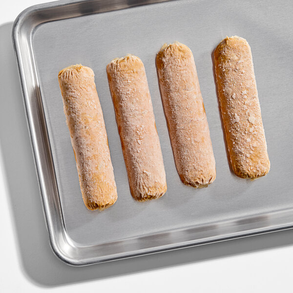 A set of four frozen plant-based vegan spicy sausages on a metal baking tray.