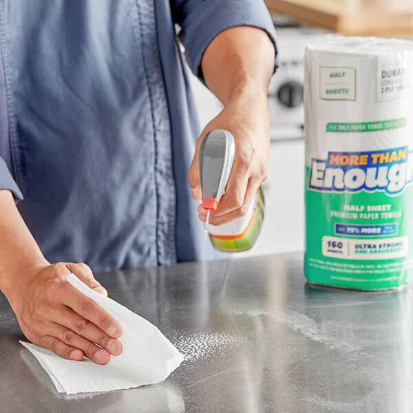 A person cleaning a counter in a professional kitchen with a Lavex paper towel.