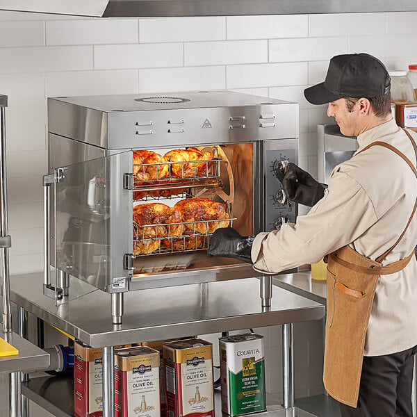 A person using a Cooking Performance Group countertop rotisserie oven to cook multiple chickens.