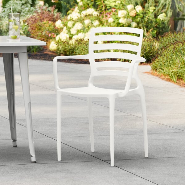 A white resin arm chair and table on an outdoor patio.