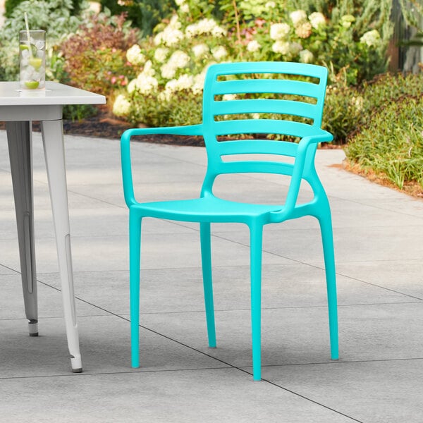 A blue Lancaster Table & Seating resin arm chair on a patio.