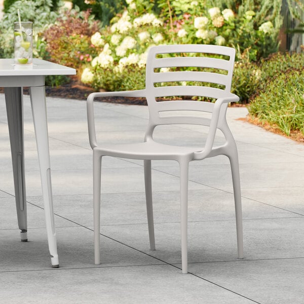 A white resin arm chair and table on a patio.