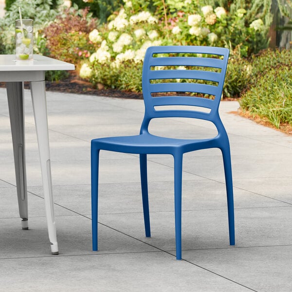 A blue Lancaster Table & Seating Sol resin chair on an outdoor patio.