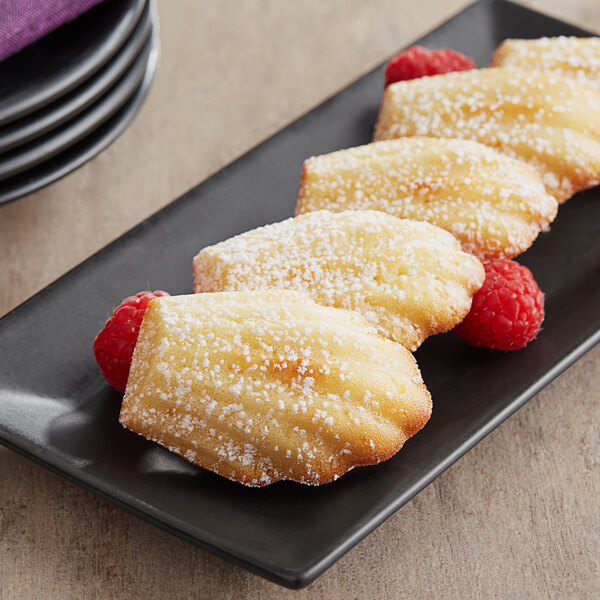 A plate of White Toque Madeleines with powdered sugar on top.
