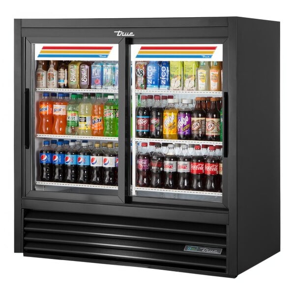 A True refrigerated sliding glass door merchandiser with LED lighting filled with drinks in a convenience store.