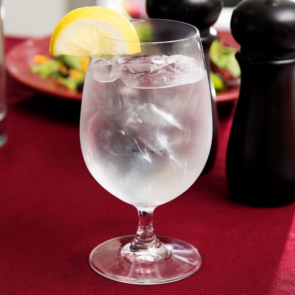 A Stolzle Weinland water goblet filled with ice water and a lemon slice.