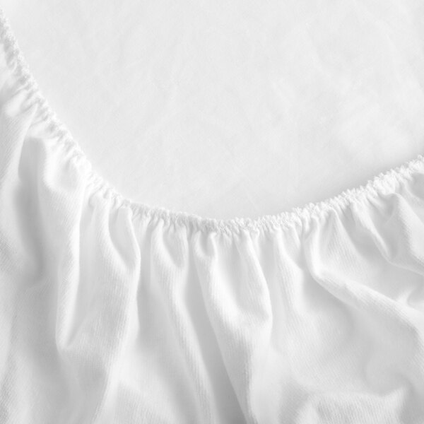 A close-up of a white polyester bed skirt with a ruffled edge.