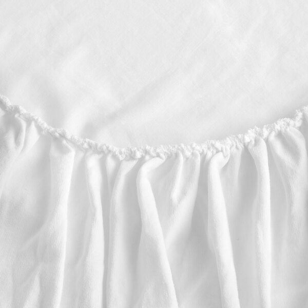 A gray bed skirt with ruffled edges.