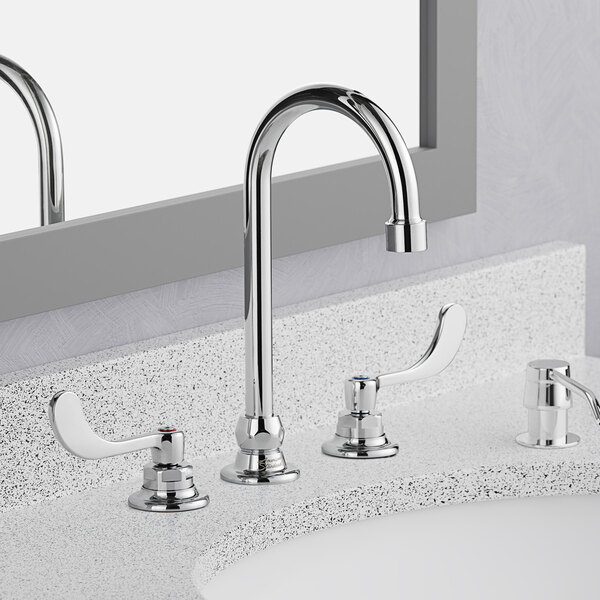 An American Standard deck-mount faucet with a gooseneck spout and wrist blade handles on a bathroom sink.
