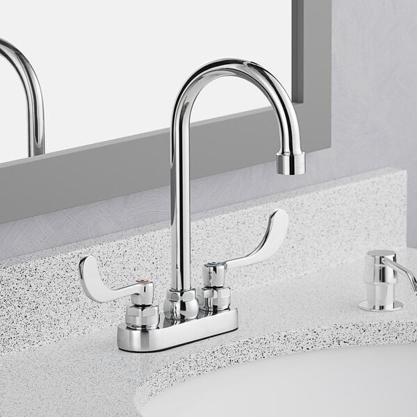 An American Standard deck-mount lavatory faucet with wrist blade handles on a countertop.