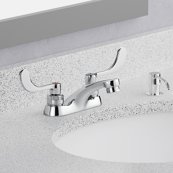 A close-up of an American Standard deck-mount lavatory faucet with wrist blade handles.
