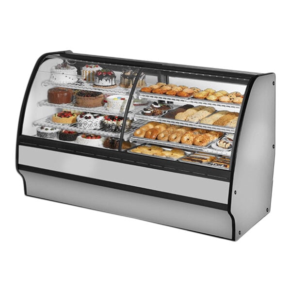 A True refrigerated dual zone bakery display case with a curved glass front and white interior holding various types of pastries.
