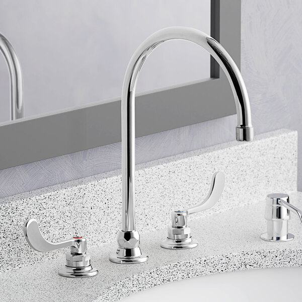 An American Standard deck-mount faucet with wrist blade handles above a sink.