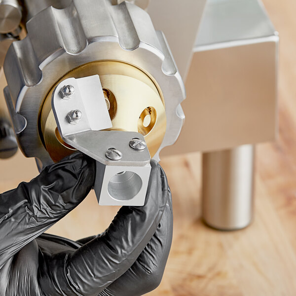 A person in black gloves holding an Estella penne pasta die with diagonal cutter kit.