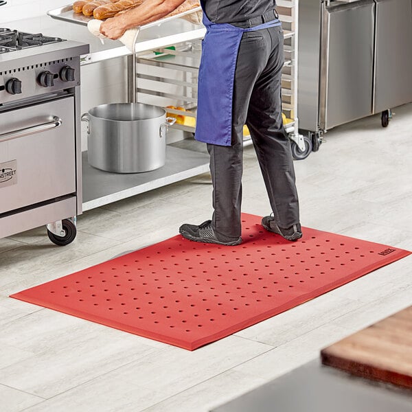 A man standing on a red Lavex anti-fatigue floor mat in a professional kitchen.
