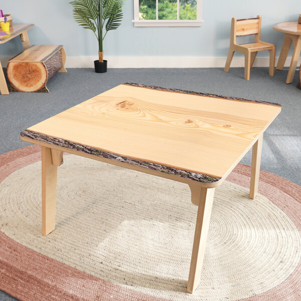 A Whitney Brothers wood table with a live edge and two wooden chairs.