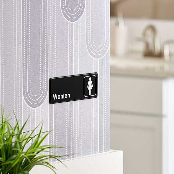 A Lavex black and white restroom sign with a woman's symbol.