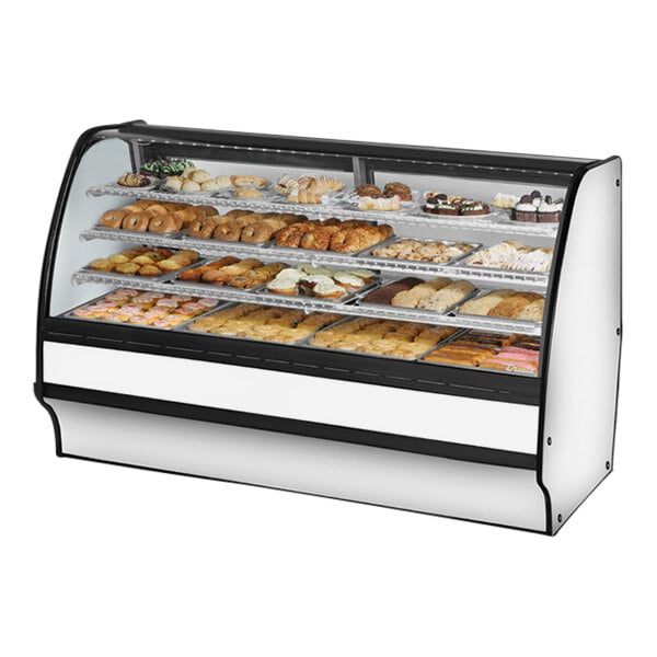A True curved glass white dry bakery display case filled with different types of pastries.