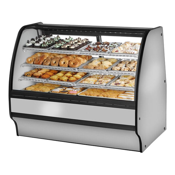 A True curved glass dry bakery display case filled with trays of pastries.