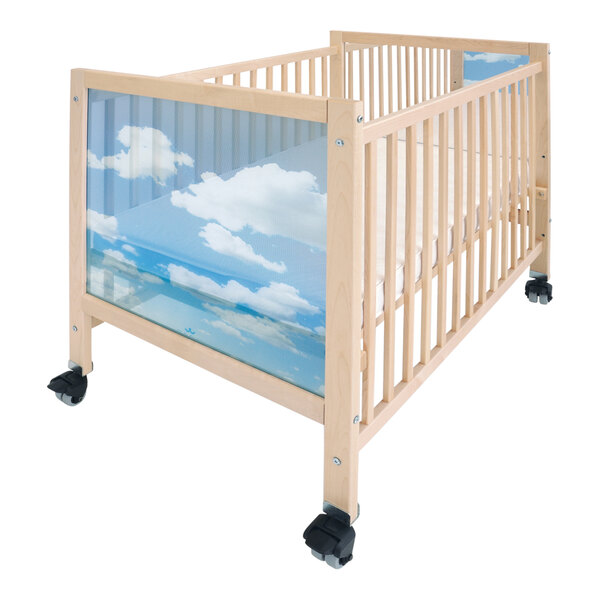 A Whitney Brothers wooden mobile crib with a glass panel and a picture of blue sky and clouds.