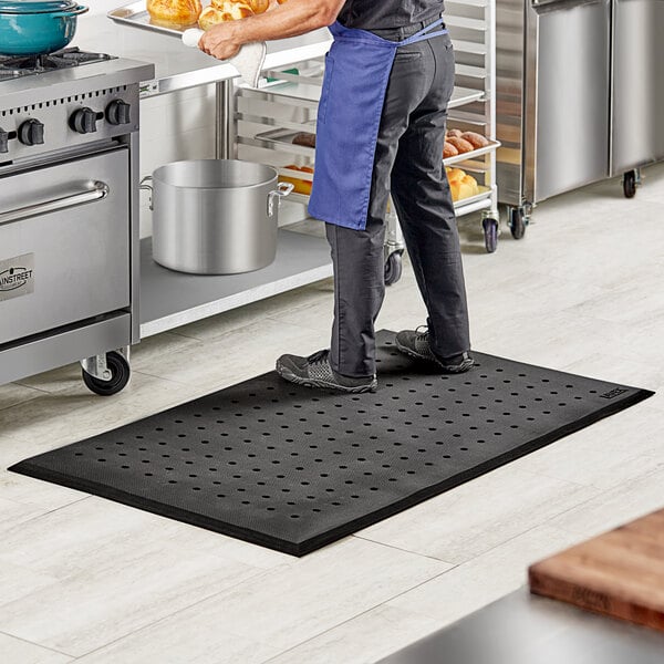 A man standing on a Lavex black anti-fatigue floor mat in a kitchen.