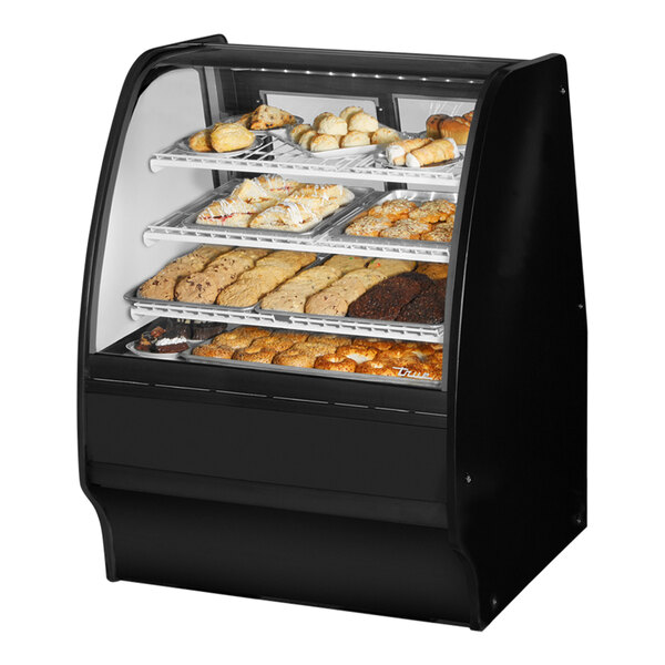 A True curved glass black dry bakery display case with various types of pastries on shelves with a white interior.