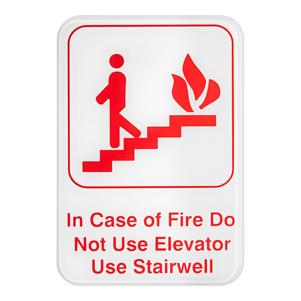 A red and white sign that says "In Case Of A Fire Do Not Use Elevator, Use Stairwell" with a person walking up stairs.