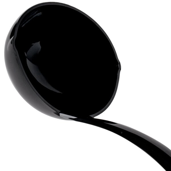 A black ladle with a long handle and a flowing liquid.