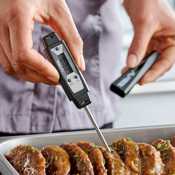 A black waterproof digital pocket probe thermometer being used to check the temperature of cooked meat.
