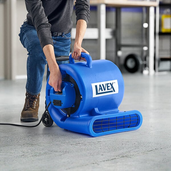 A man using a Lavex blue air mover to clean a floor.