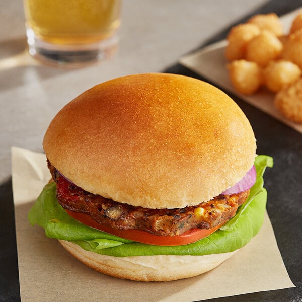A plant-based Brioche burger bun with a burger and potato balls on a plate.