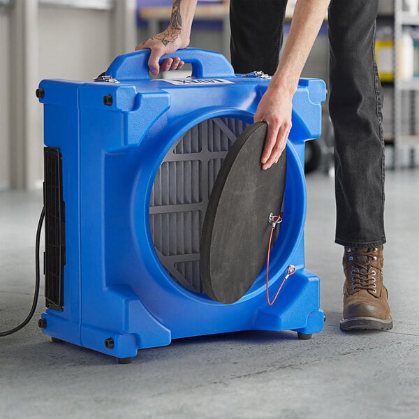 A person using a Lavex 2-Stage HEPA Filtration Air Scrubber in a room.