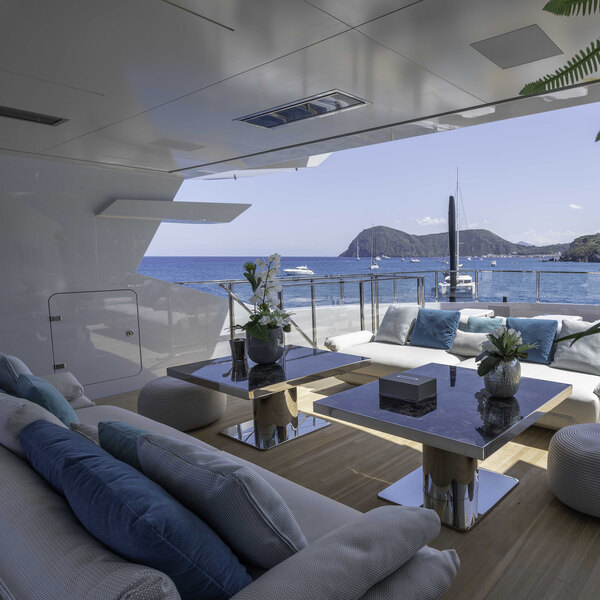 A Bromic Heating black outdoor patio heater on a boat with a table and chairs and a vase of flowers on the table.