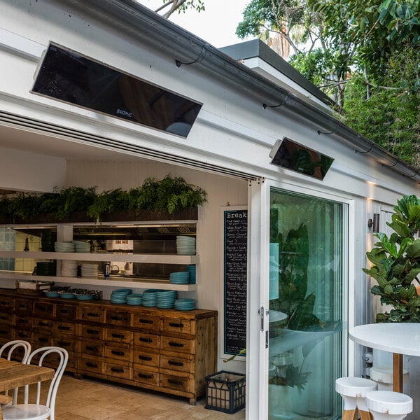 A black Bromic Heating Platinum Smart-Heat electric outdoor patio heater mounted above a patio area.
