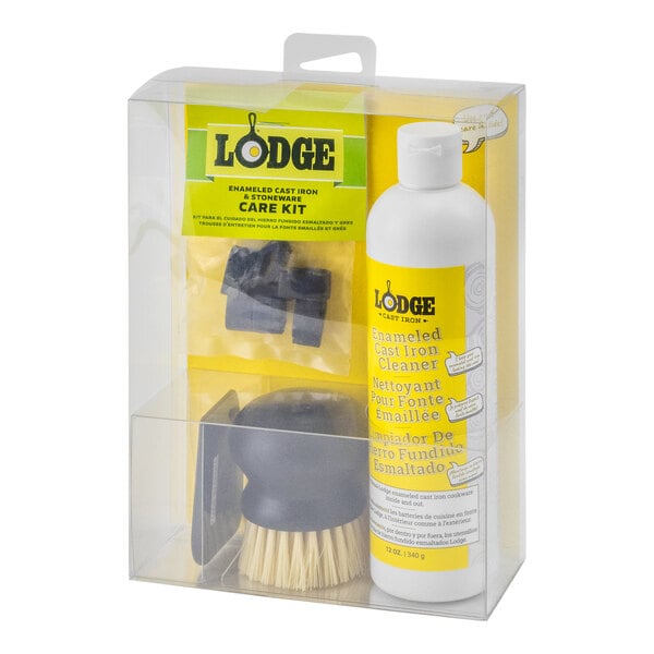 A clear plastic box with a yellow and white Lodge enameled cast iron cleaning kit including a brush and sponge.