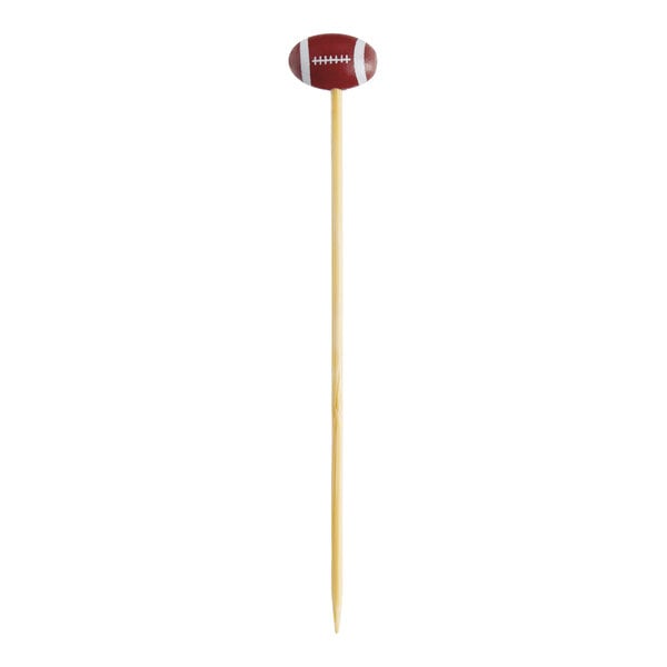 A bamboo cocktail pick with a small football decoration at the top.