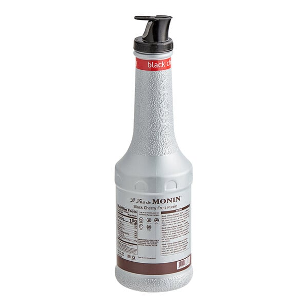 A close-up of a white Monin Black Cherry Fruit Puree bottle with a black lid.