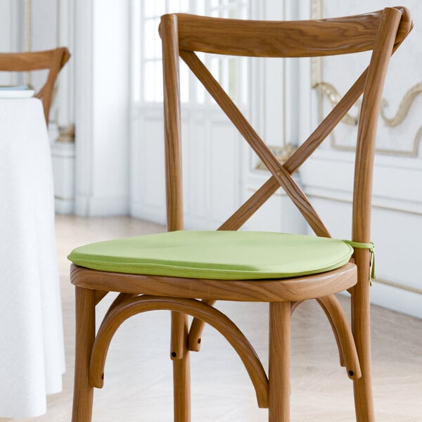A Lancaster Table & Seating wooden chair with a green cushion tied to the seat and back.