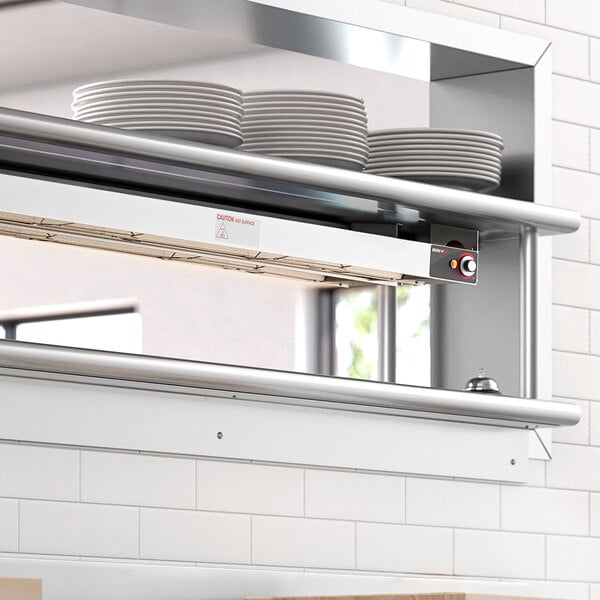 A ServIt double strip warmer on a counter in a professional kitchen above a shelf with plates.