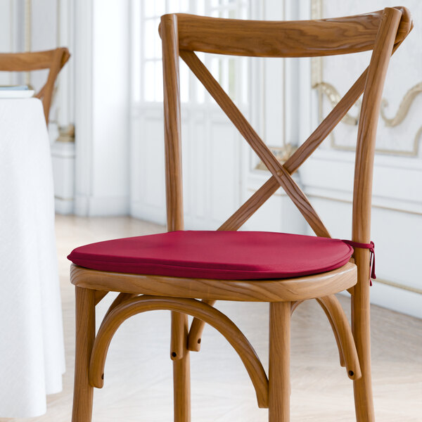 A Lancaster Table & Seating wooden chair with a merlot red cushion on the seat and back.