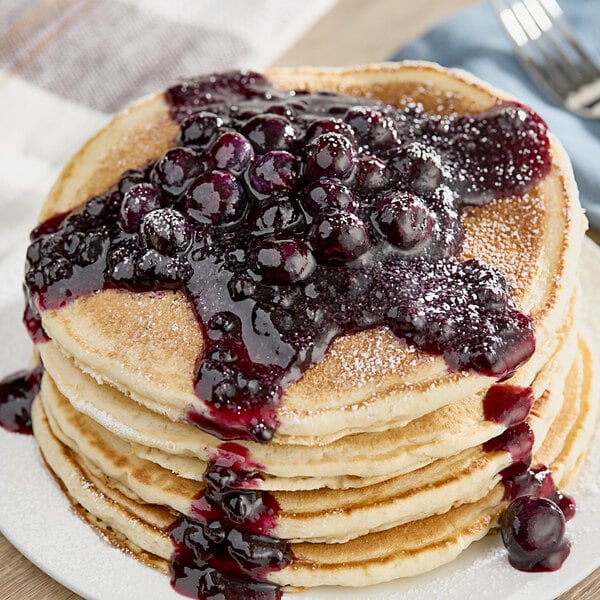 A stack of pancakes topped with Monin blueberry puree.