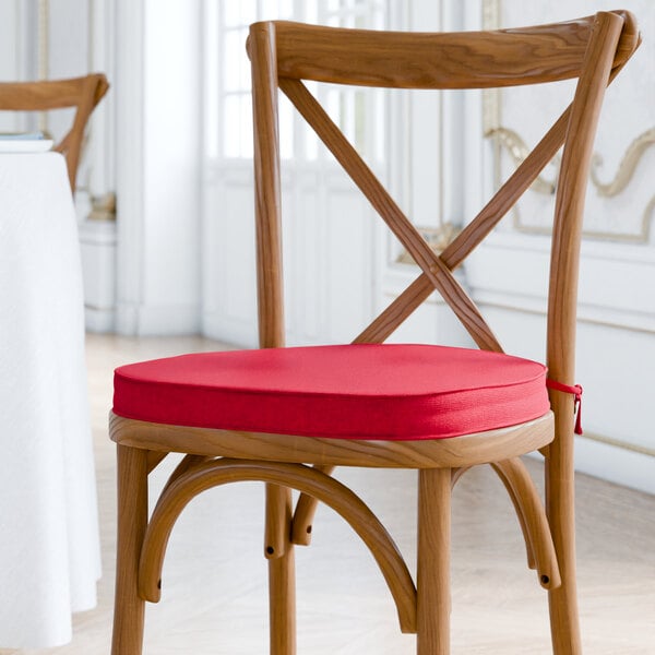 A Lancaster Table & Seating wooden chair with a red cushion tied to it.