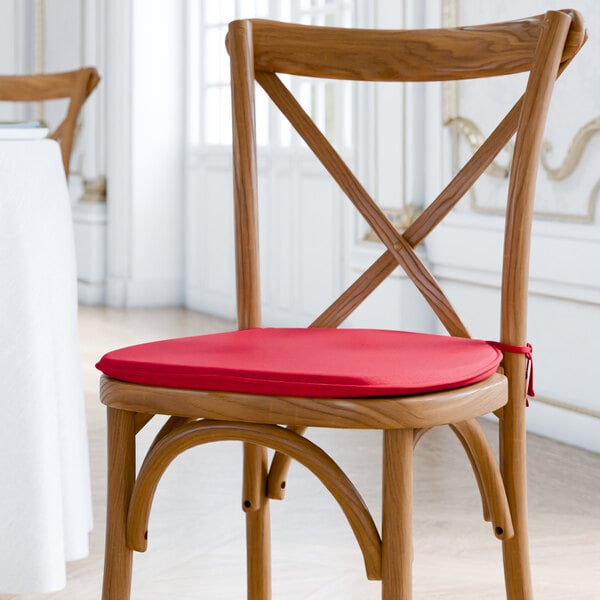 A Lancaster Table & Seating wooden chair with a red cushion with ties.