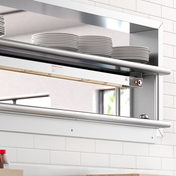 A ServIt strip warmer on a stainless steel shelf above plates.