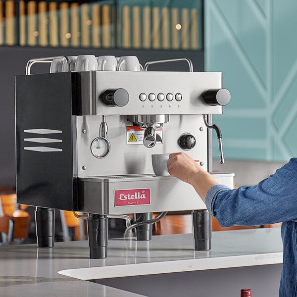 A person using an Estella Caffe espresso machine to pour a cup of coffee.