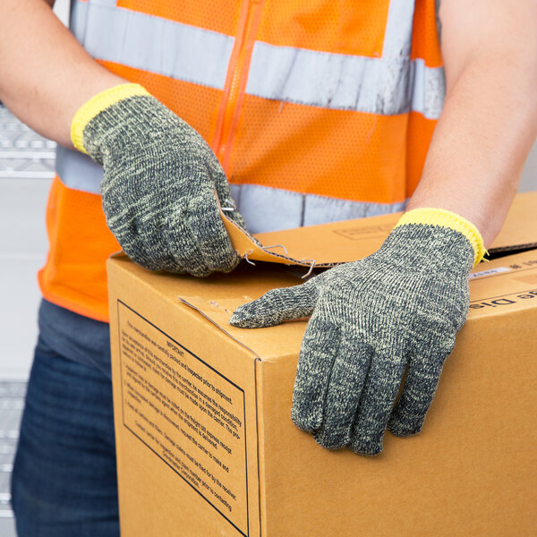 A person wearing Cordova Power-Cor Max Camo cut-resistant gloves holding a box.