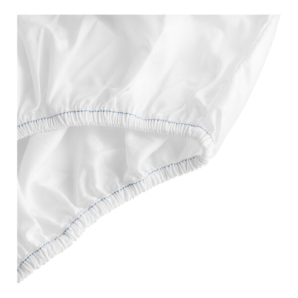 A close-up of a white Garnier-Thiebaut fitted sheet with blue stitching.